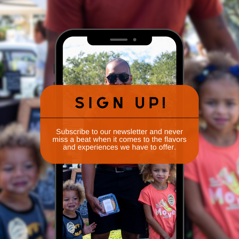 A smartphone displaying a "sign up for our Holiday Rum Box!" advertisement held by a person, with blurred children and adults in the holiday spirits outdoors.