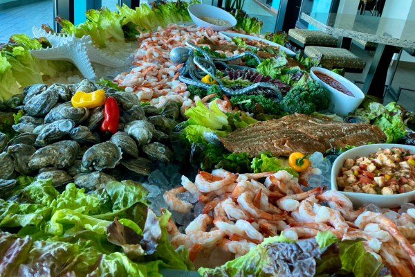 A seafood buffet featuring an array of shrimp, oysters, fish, and various salads on a bed of lettuce with decorative elements is perfect for holiday catering. Wow your guests with this exquisite spread that promises both variety and elegance.