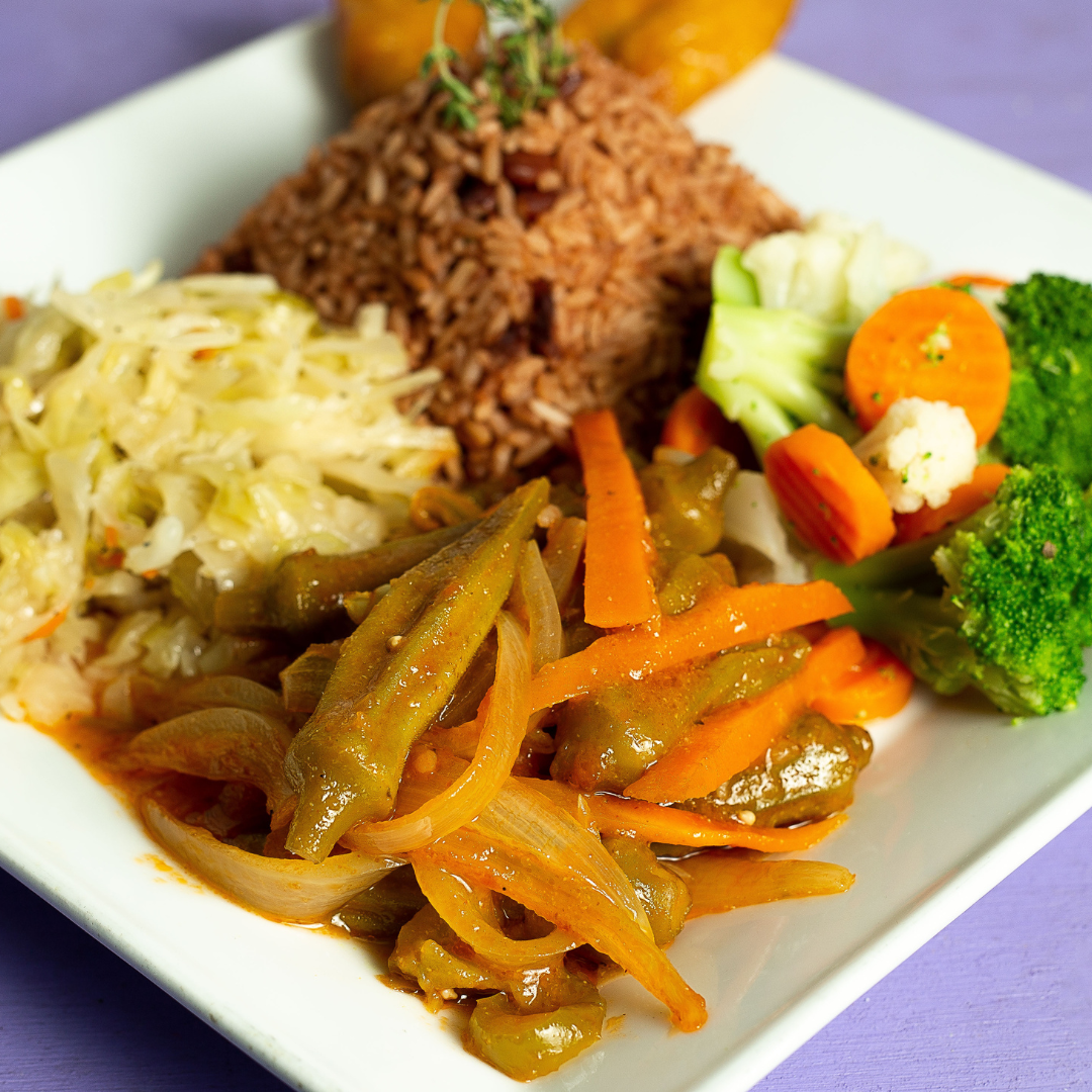An island-inspired square white plate with rice and peas, steamed cabbage, mixed vegetables, and stewed okra and carrots—perfect for a healthier you or as part of your New Year's resolution.